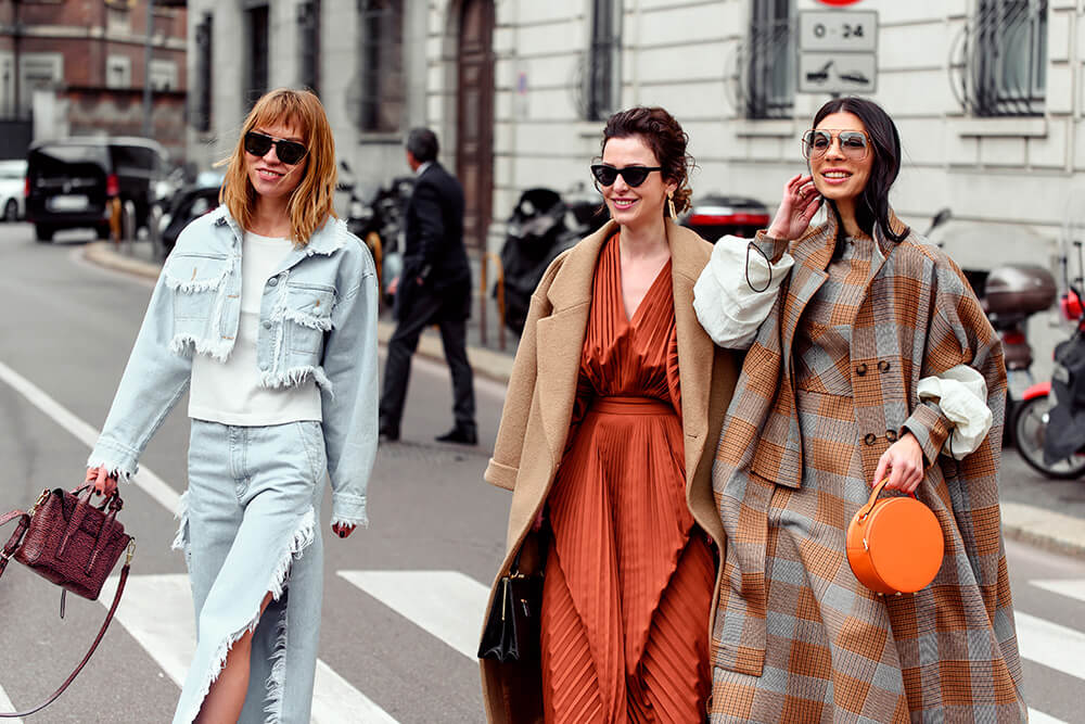 três mulheres em uma rua, com looks referência em street style, ou moda de rua